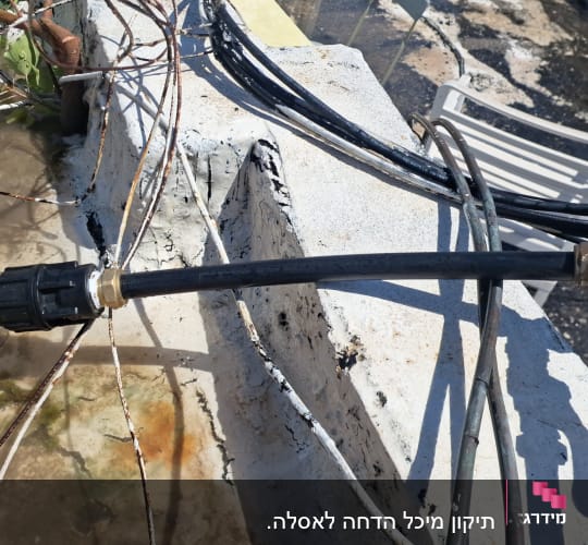 צינור מים עם ברז ומחבר על קיר בטון